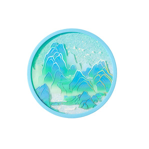 Round turquoise makeup compact with a blue-green mountain landscape design