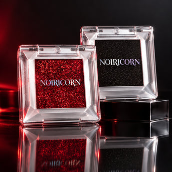 NOIRICORN Ruby Flame and Noir Spark: two closed square single-eyeshadow compacts in a compact red-and-black editorial arrangement.